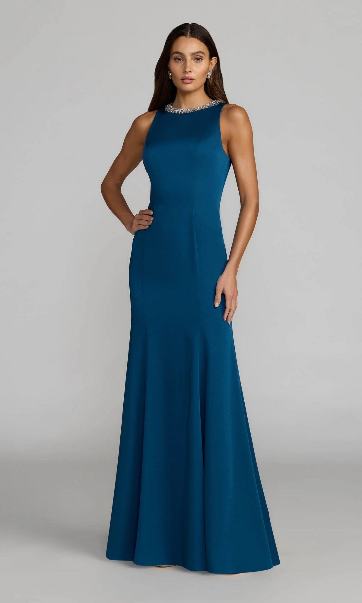 Woman wearing the Beaded-Neck Long Prom Dress by Mac Duggal (style 49093), a floor-length, sleeveless gown in stunning ocean blue with a fitted bodice and flared skirt, standing against a plain gray background.